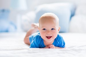 Ein lachendes Baby strahlt in die Kamera.