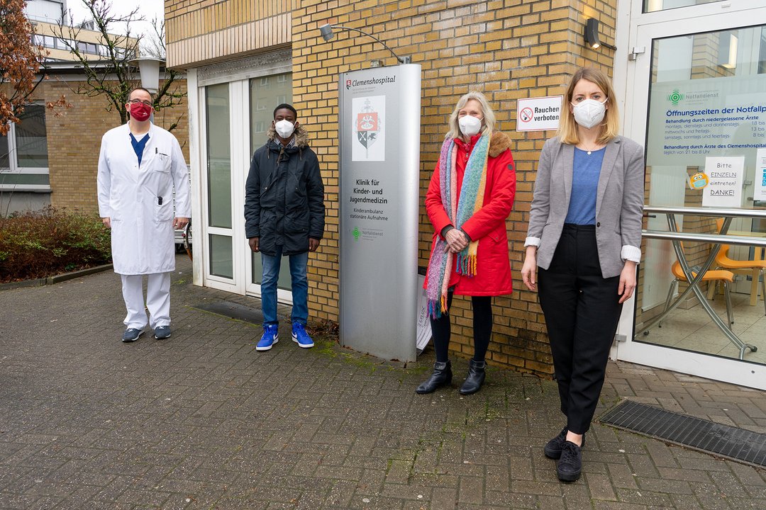 Vier Menschen stehen vor der Kinderambulanz des Clemenshospitals