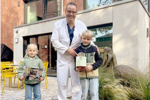 Zwei Kinder übergeben die Spende an Dr. Debus
