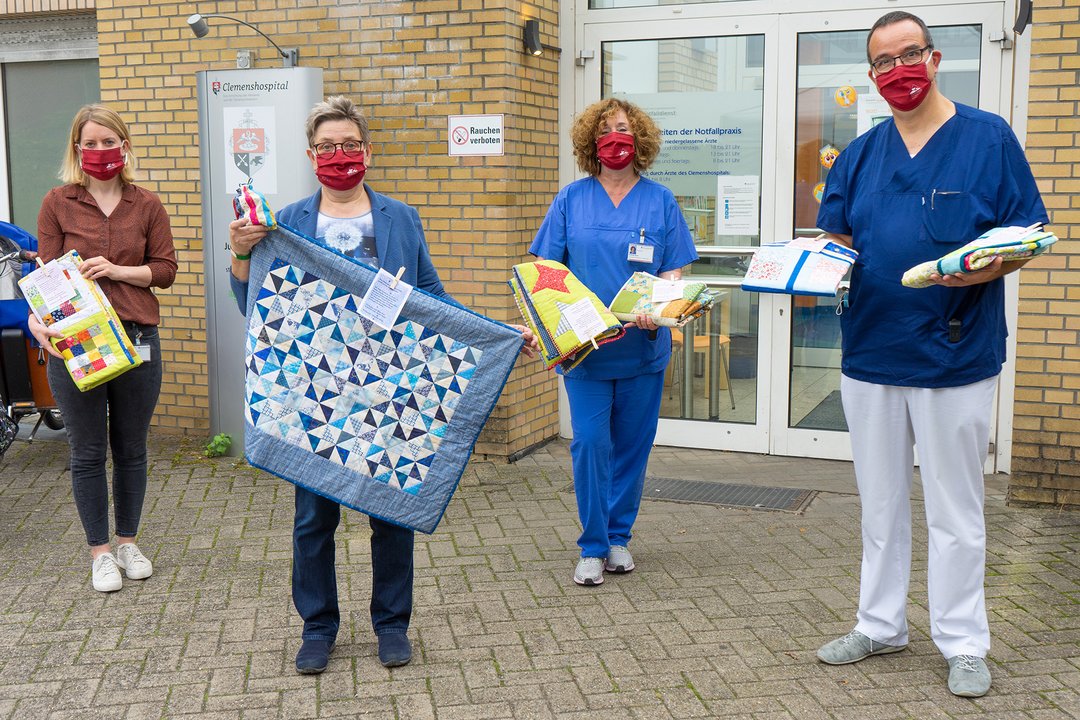 Mehrere Personen präsentieren bunte Stoffdecken