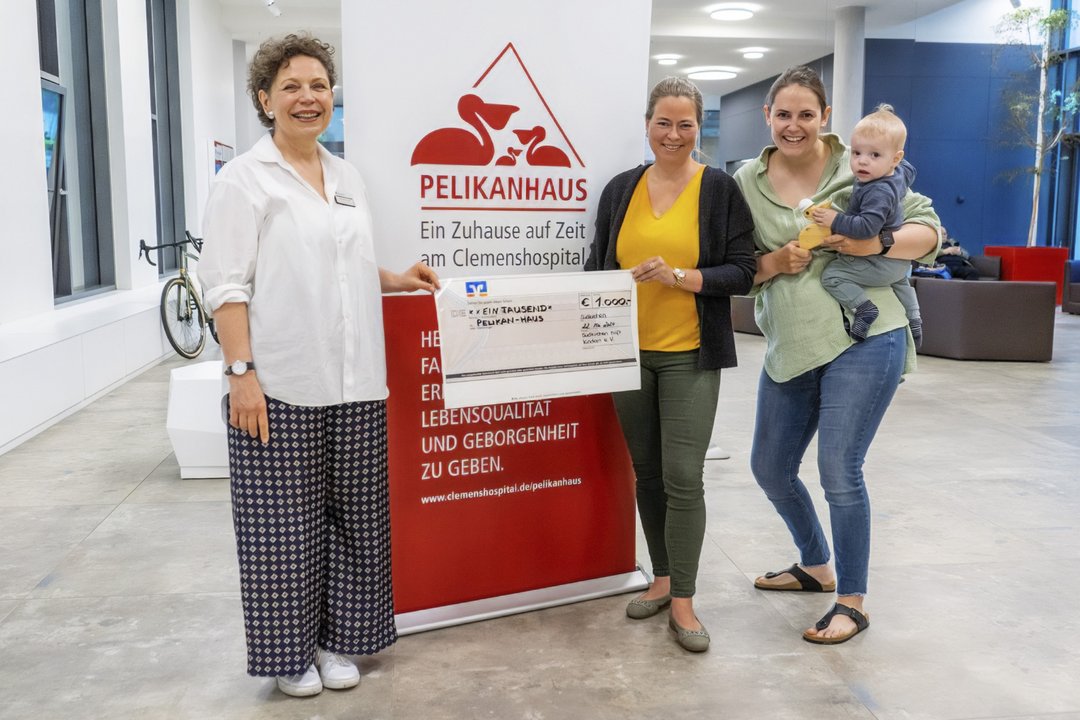 Drei Personen halten einen Scheck