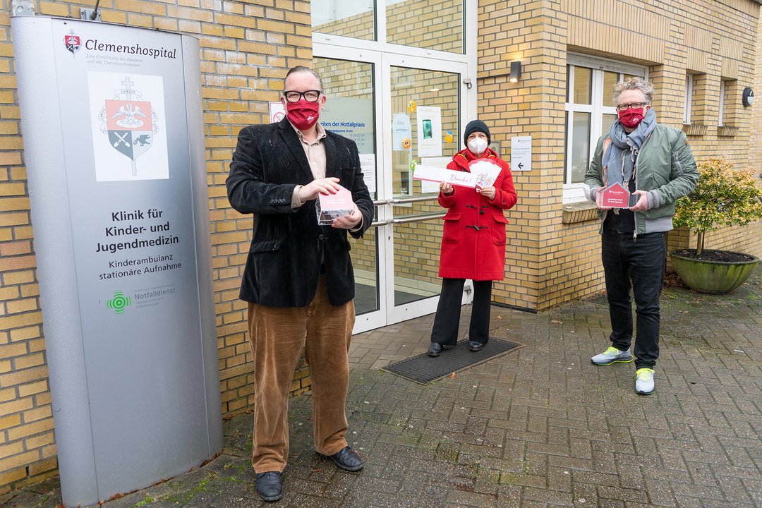 Drei Personen stehen vor der Kinderklinik
