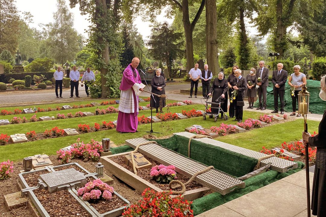 Mehrere Ordensschwestern an einem Grab