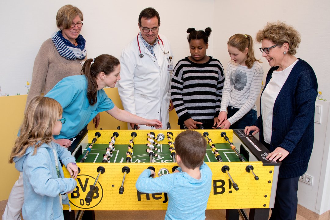 Der BVB-Kicker Mitarbeiter des Clemenshospitals und ein paar Kinder spielen mit dem neuen Kicker der Kinderklinik.