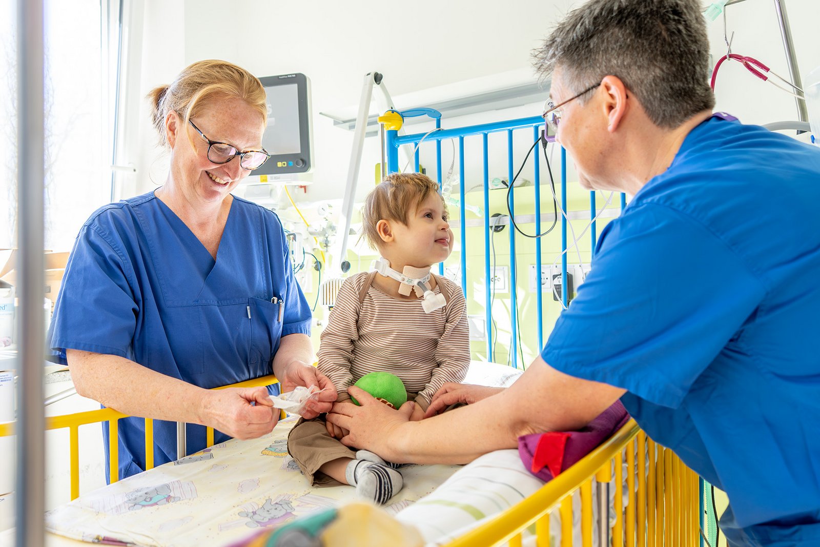 Ein kleines Kind wird von zwei Pflegekräften behandelt