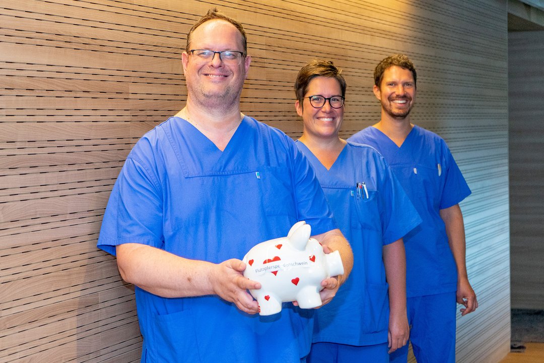 Drei Personen halten ein Sparschwein